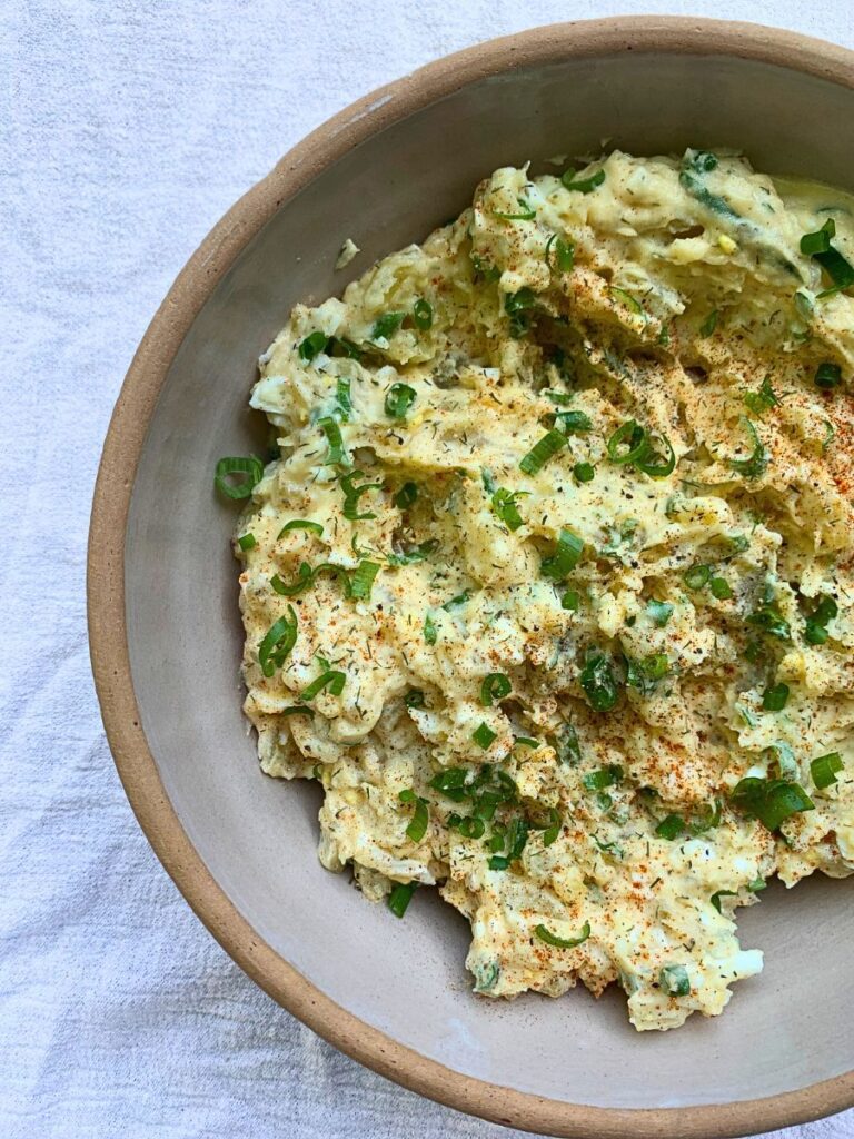 homemade potato salad served in a pottery bowl topped with garden fresh green onions for June family dinner